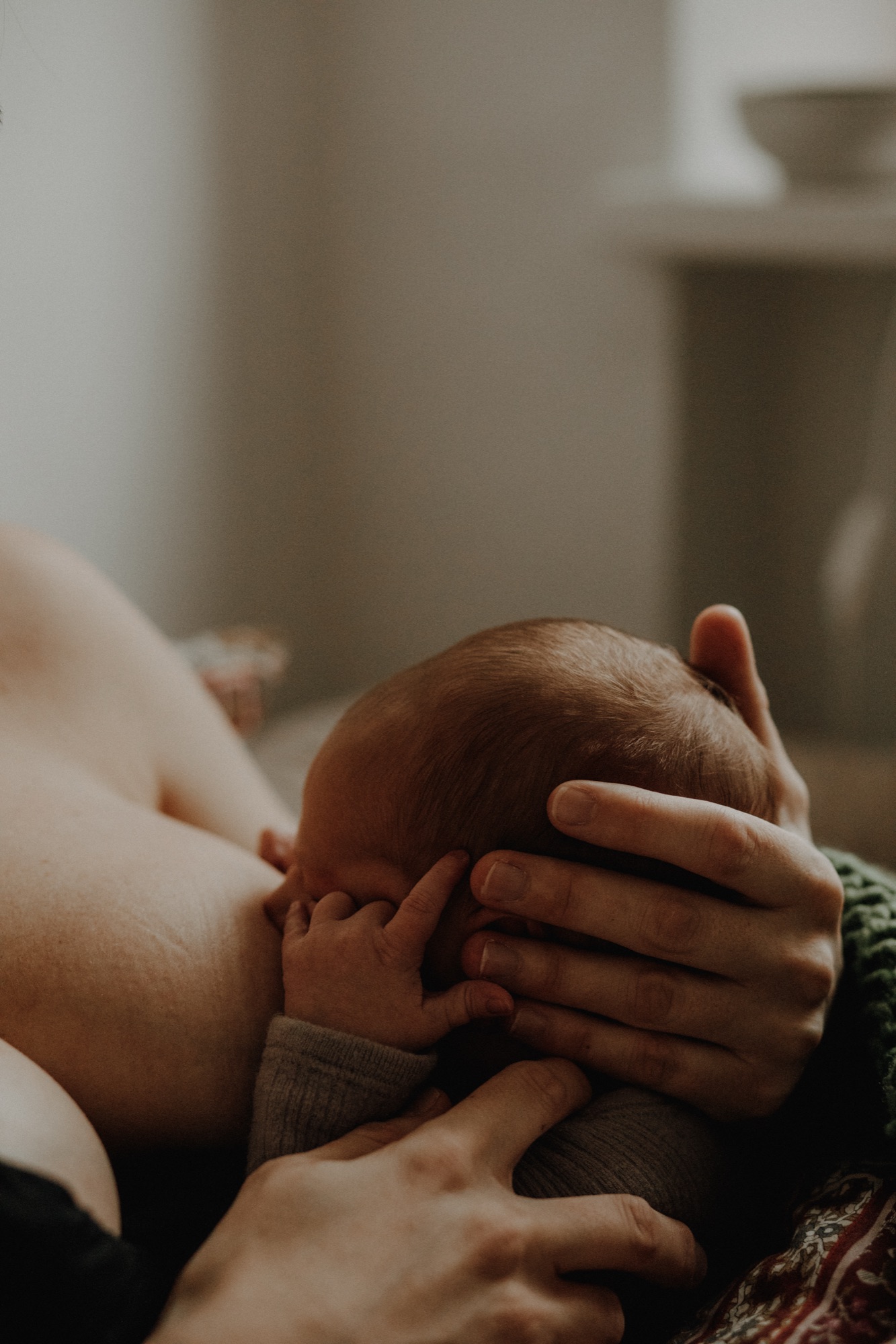 Therapist gently holding a relaxed woman's head during a massage session with warm natural lighting.